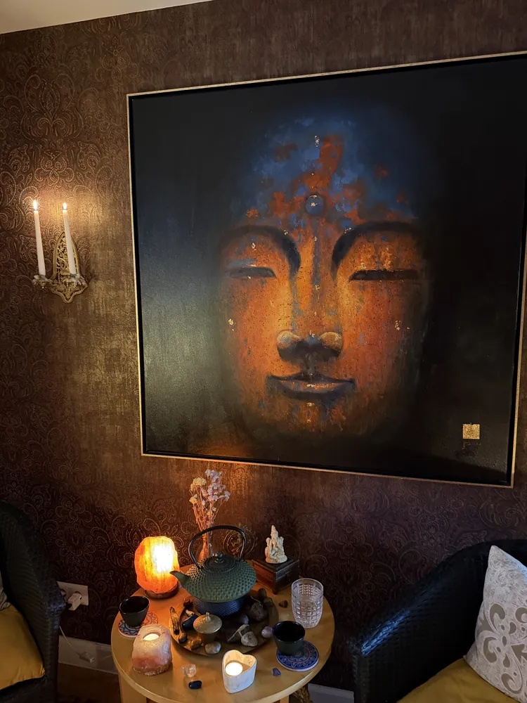 Buddha-Bild über einem Tisch mit Kerzen und Klangschale