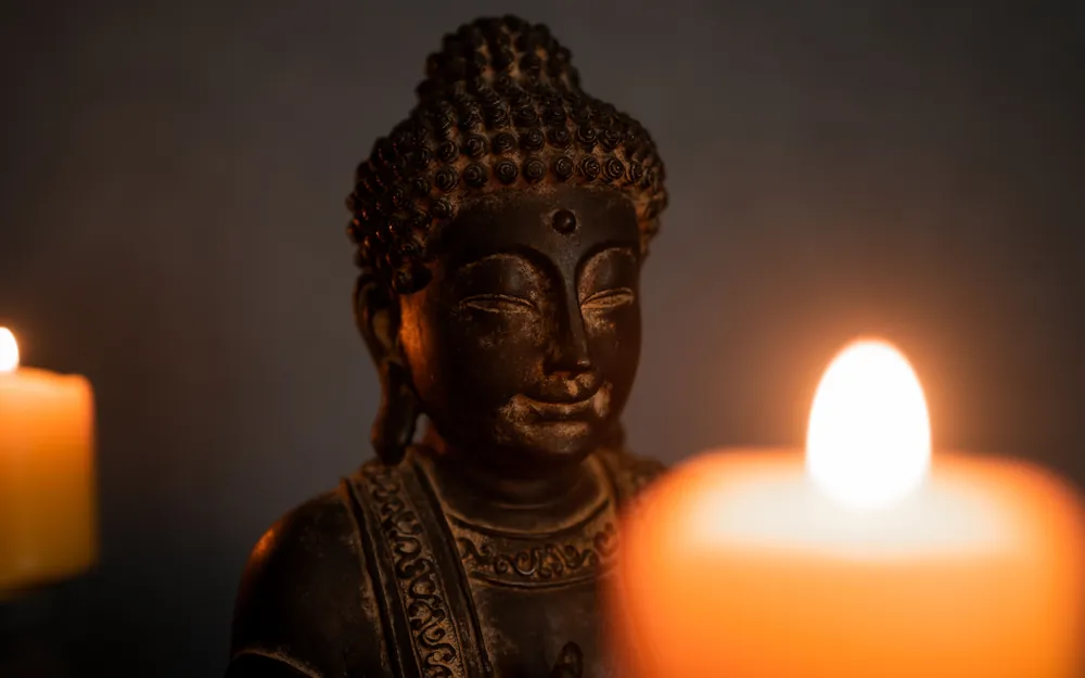 Buddha-Figur neben einer brennenden Kerze