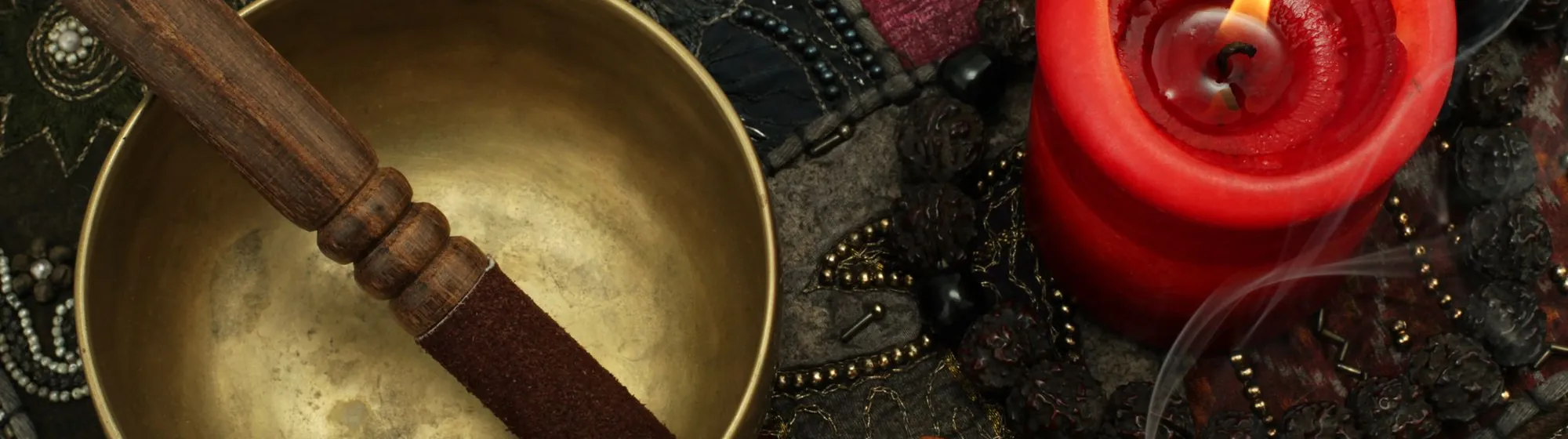 Klangschale und rote Kerze auf orientalischem Tuch